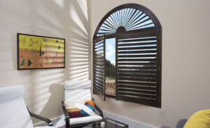 Custom dark timber arched plantation shutters installed on a feature window in a Melbourne home by Complete Blinds.